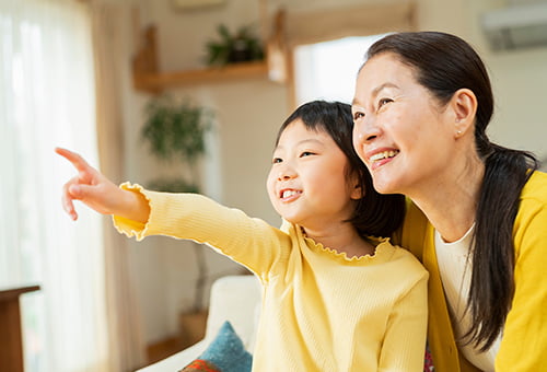 リビングで孫と過ごす祖母の写真