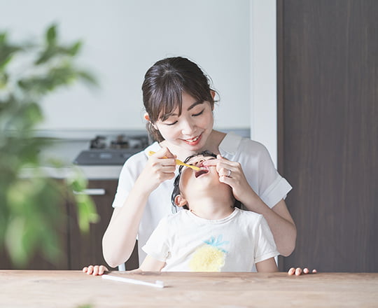 子供の歯を磨く母親の写真